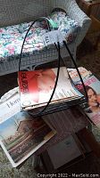 Black metal MCM magazine rack holding vintage magazines including Chatelaine and Canadian Home.