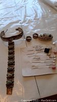 Full lot showing bracelet, rings, pill box, and hat pins on a plastic-covered table