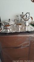 Photo showing the complete silver plate tea and coffee service set arranged on the ornate silver tray with visible copper base.