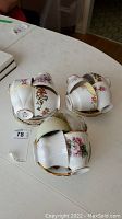 Three stacks of teacups and saucers showing various floral patterns and gold trim; teacups stacked upside down on saucers.
