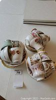 Twelve bone china tea cups and saucers in floral patterns and gold trims placed on a table