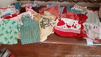Photo showing multiple vintage handmade aprons spread across furniture, with vibrant red, green, yellow, and patterned fabrics.