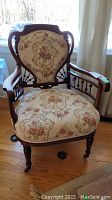Front view of vintage ornate wooden chair with floral patterned upholstery showing overall design and condition.