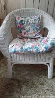 Front view of white wicker armchair with floral seat and back cushions