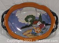 Front view of the Noritake Morimura lusterware oval serving bowl showing painted landscape and orange border with black handles.