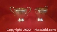 Photo showing first set of vintage electroplated silver cream and sugar containers with textured detailed handles and bands near rims