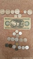 Photo showing assorted international coins arranged in rows above and below a Hungarian 10 Tizforint banknote.