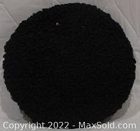 Top-down view of round black Persian lamb tam hat showing texture and hat pin