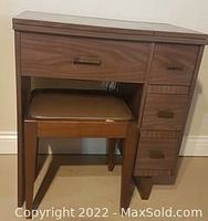 Wooden sewing table in closed position with matching padded stool under it