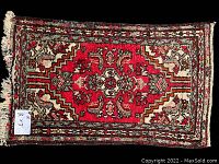 Full view of the red handmade antique/vintage Iranian rug showing overall pattern and fringe edges.