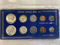 Front view of two 1964 US Mint Sets in blue holders showing coins from Philadelphia and Denver Mint collections with visible toning.