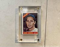 Front view of 1966 Topps Sandy Koufax baseball card featuring his portrait and team name in thick screw down plastic case with gold screws.