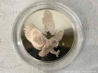 Obverse of the silver Elf Owl medal showing engraved owl images and the artist mark.