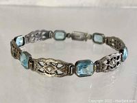 Angled view of entire bracelet showing alternating filigree and blue stone links