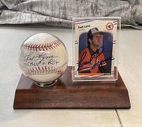 Display of hand-signed baseball and autographed Fleer baseball card on wooden stand