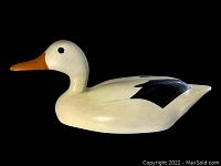 Side profile view of the hand painted wooden duck decoy showing white body, orange beak, and black wing details.