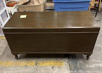 Front view of closed hope chest with dark stained wood and four small legs.