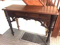 Front view of antique console table showing drawer and turned front legs