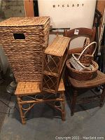 Photo showing large rectangular woven hamper, rattan side table, wooden chair with curved backrest, and several baskets stacked on chair and table