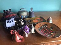 Overview of the lot showing a cat-shaped decorative item, brass bells, a rectangular tray, and enamelware items.