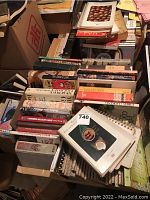 Pile of assorted hardcover and spiral bound cookbooks stacked randomly