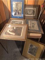 Group of five framed prints stacked on table