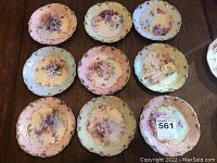 Nine Limoges porcelain tea plates arranged on wooden table