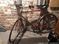 Full side view of the red vintage Norco Monshee men's touring bicycle showing frame, front basket, handlebars, pedals, saddle, front and rear wheels, and rear fender.