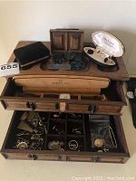 Wooden jewelry box open showing hinged lid and removable velvet tray with compartments filled with small jewelry pieces