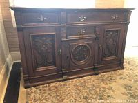 Full view of the antique wooden buffet showing overall design, carvings, and brass hardware.