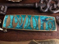 Brass pen tray with turquoise ceramic inlay alongside keys and letter opener