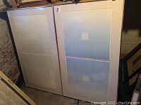 Two framed prints leaning against brick wall, showing overall size and appearance