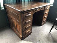 Front side view of the vintage wooden desk showing pedestal drawers on both sides and keyhole lock