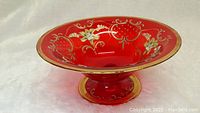 Front angle view of the ruby red glass dish showing gold floral decoration inside the bowl.