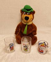 Close up photo of Yogi Bear stuffed animal and the three cartoon glass mugs showing character details clearly.