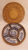 Photo of round woven wicker basket lid placed behind the divided ceramic serving dish showing cobalt blue floral design, five section layout.