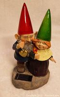 Pair of two garden gnome statues with solar panel at base, showing red and green hats, detailed facial features and clothing.