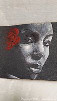 Close-up of the hand painted face of a lady with a red Mexican rose in her hair on the skateboard deck.