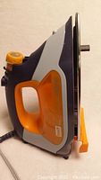 Side profile of orange and gray Oliso Smart Iron showing the handle and soleplate.