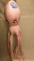Side view of pink giant squid dog toy showing shell design and expressive eyes.