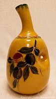 Front view of the vintage ceramic olive oil pourer showing the olive leaf decoration and mustard yellow glaze