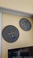 Photo of metal wall clock and thermometer mounted on beige wall showing weathered condition and design details.