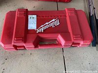 Closed red plastic carrying case labeled Milwaukee, heavy duty orbital saw designation on auction tag