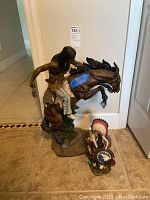 Both Native American Indian figurines together, showing scale and condition on floor indoors.