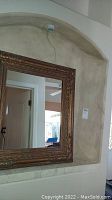 Mirror installed in a wall niche reflecting parts of a room including doorways and ceiling fan.
