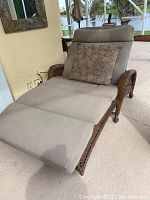 Frontal view of oversized wicker lounge in an outdoor covered patio setting, showing beige cushions and a decorative pillow.