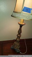 Close-up of upper portion of the lamp showing fabric lampshade with decorative trim and part of the ornamented base.