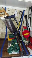 Full view of lot showing hand saws, wrench bar, extension cords, hammers and miscellaneous tools arranged on pegboard