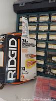 RIDGID 25 ft indoor/outdoor extension cord box next to storage drawers with labeled compartments