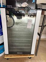 Front view of Wine Enthusiast wine refrigerator showing glass door, wire shelving, and digital display on the door.